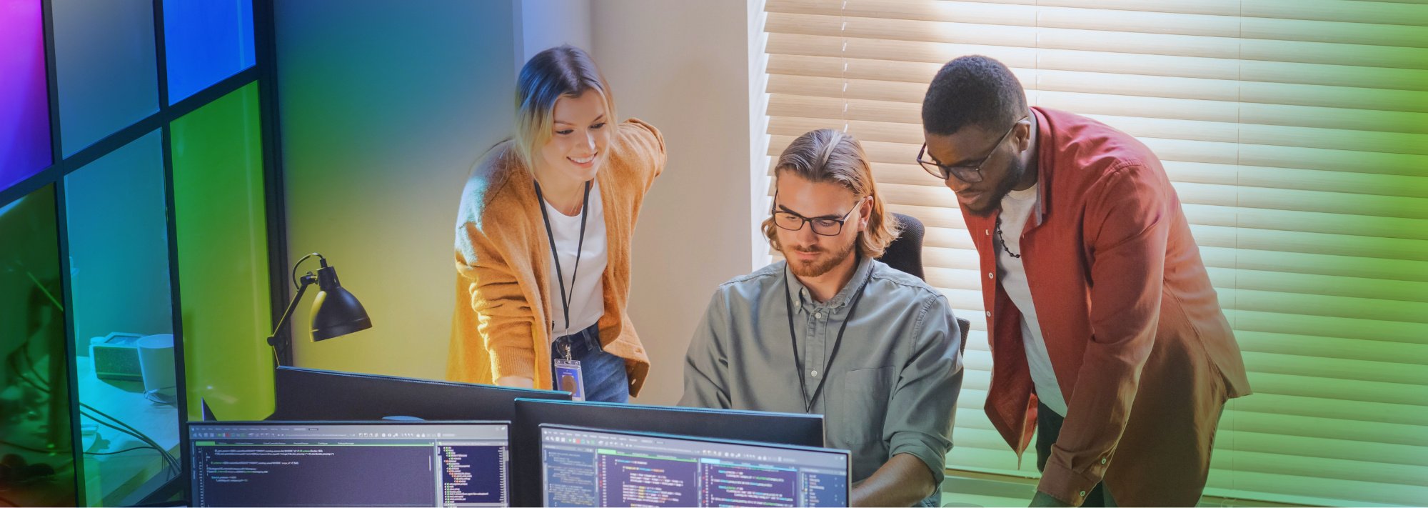 Equipo de Desarrollo en un proyecto con Gestión de Calidad del Software trabajando en una oficina frente a las computadoras viendo código de software