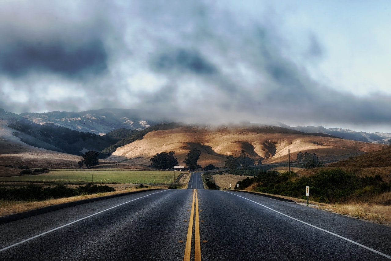 Una carretera con el horizonte cubierto por nubes, que representa el camino que sigue tu personal cuando atiende la solicitud de un cliente.